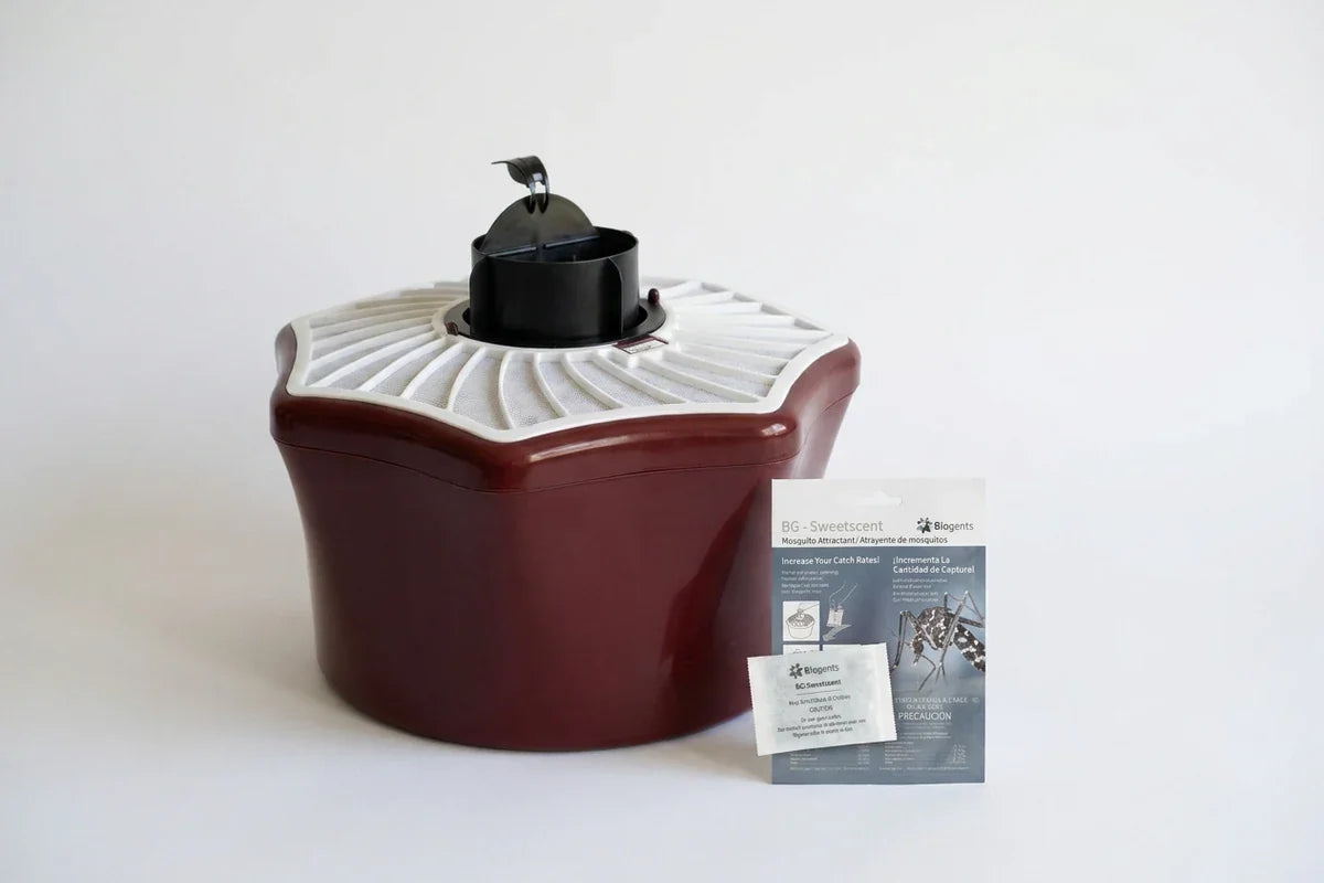 Dark red mosquito trap beside Biogents BG-Sweetscent packaging and a sachet.