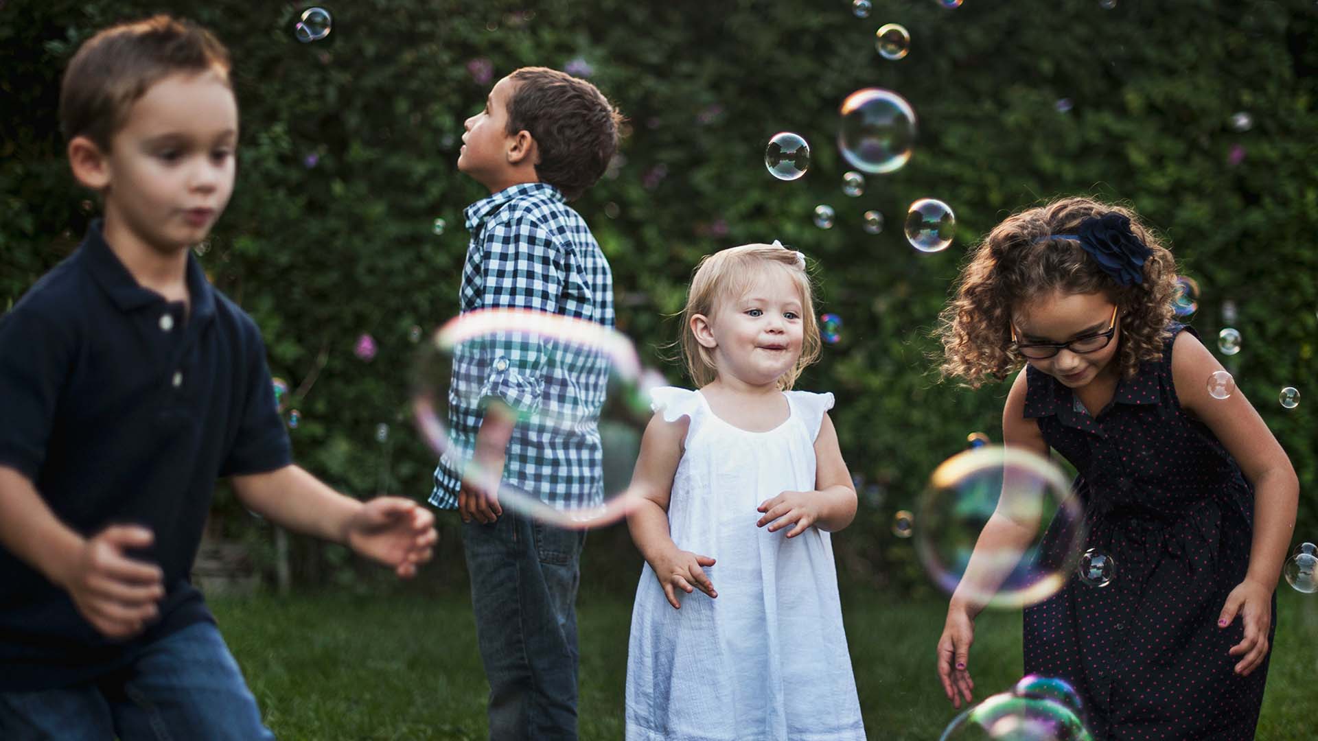 Children playing with soap bubbles in a garden.