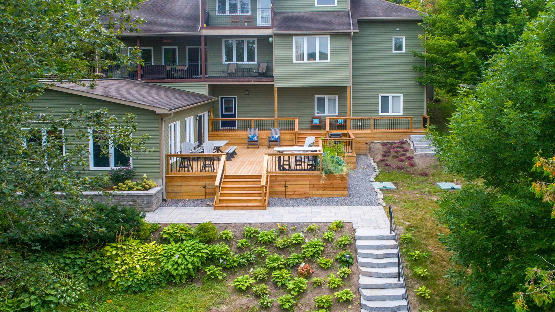 Two-story green house with spacious wooden deck and landscaped garden
