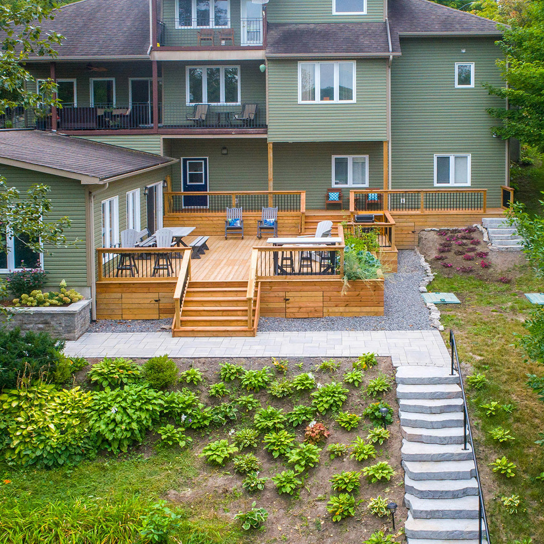Two-story green house with spacious wooden deck and landscaped garden