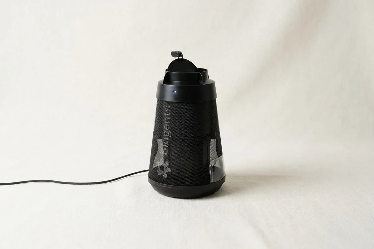 Black cylindrical electronic device with mesh body, handle, cord, and blue indicator light.